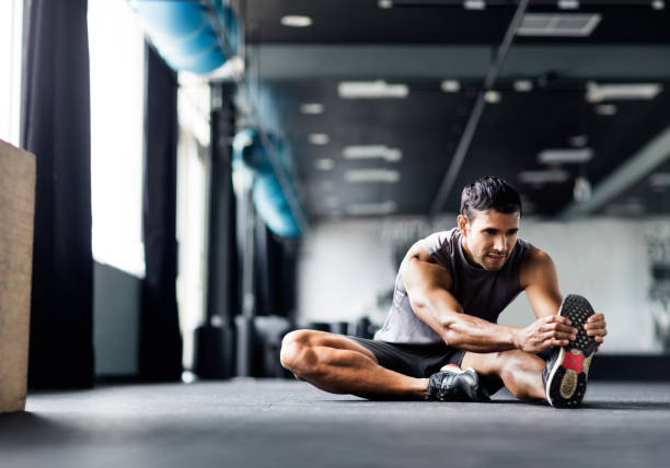 Young man doing leg stretches in the gym.